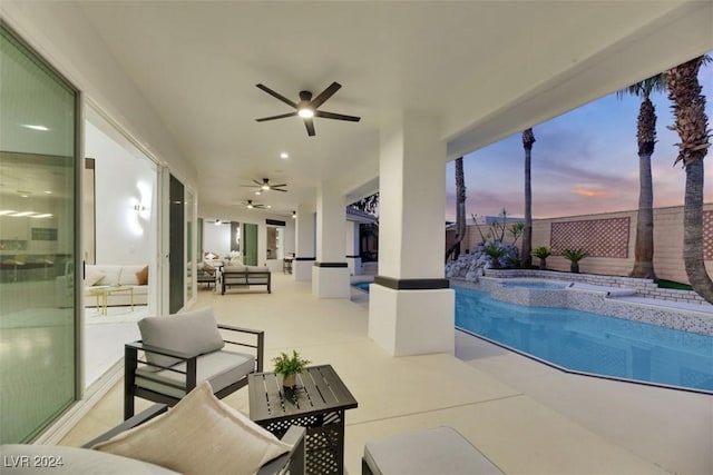 pool at dusk featuring an in ground hot tub, an outdoor living space, a patio, and ceiling fan