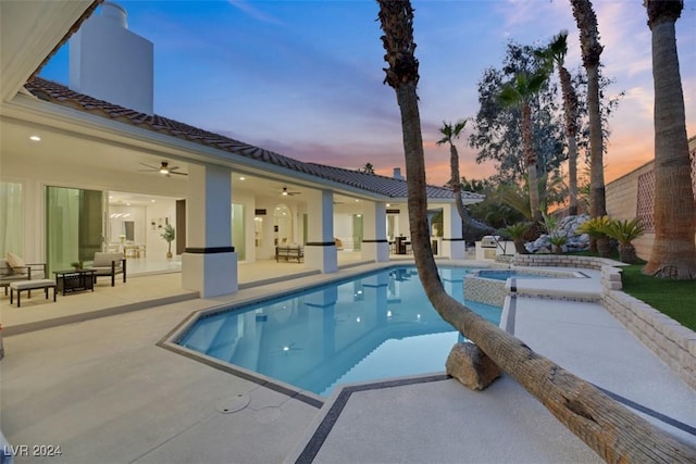 pool at dusk featuring ceiling fan, an in ground hot tub, and a patio