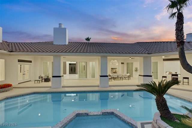 back house at dusk with a swimming pool with hot tub, an outdoor hangout area, and a patio area