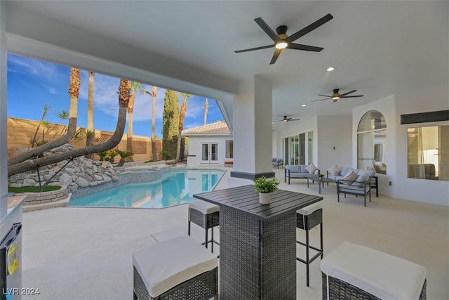 view of swimming pool with outdoor lounge area, a patio area, and ceiling fan