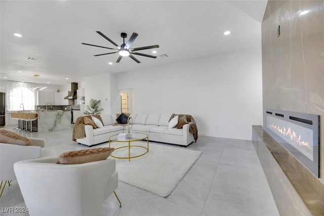 living room featuring a fireplace, ceiling fan, and sink