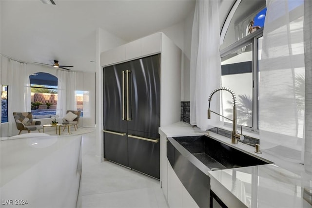 kitchen featuring ceiling fan, high end fridge, white cabinets, and sink