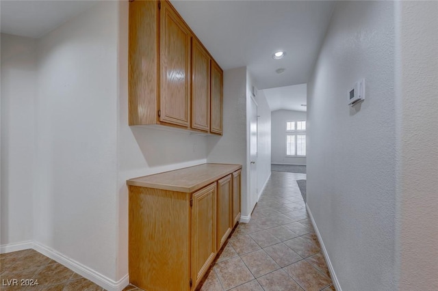 hall with light tile patterned floors and lofted ceiling