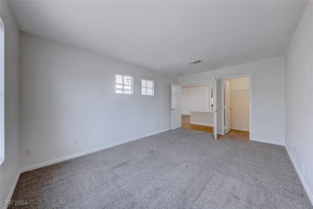 unfurnished bedroom with carpet flooring, a walk in closet, and a closet