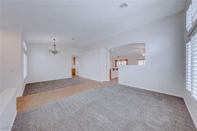 unfurnished room with ceiling fan with notable chandelier, light tile patterned flooring, and lofted ceiling