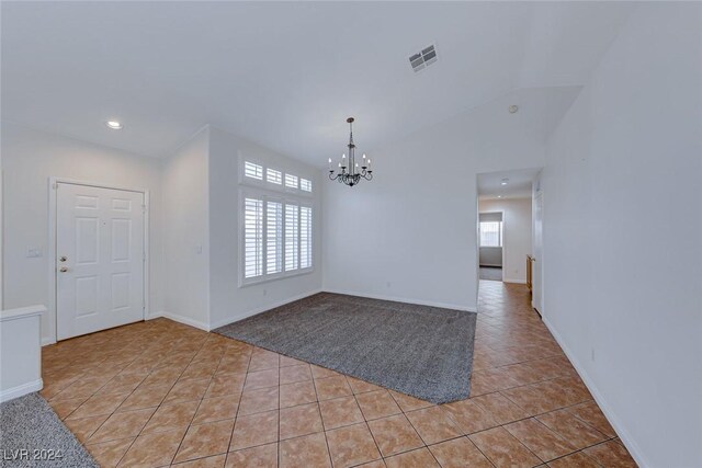 spare room featuring light tile patterned flooring, vaulted ceiling, and an inviting chandelier