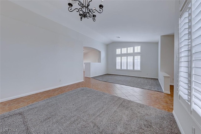 tiled spare room featuring vaulted ceiling and an inviting chandelier