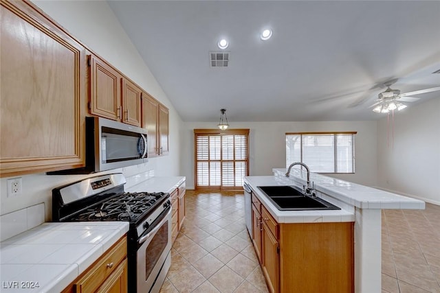 kitchen featuring sink, an island with sink, a wealth of natural light, appliances with stainless steel finishes, and tile counters