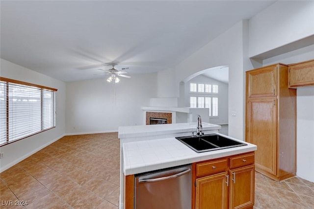 kitchen featuring tile countertops, dishwasher, lofted ceiling, sink, and ceiling fan