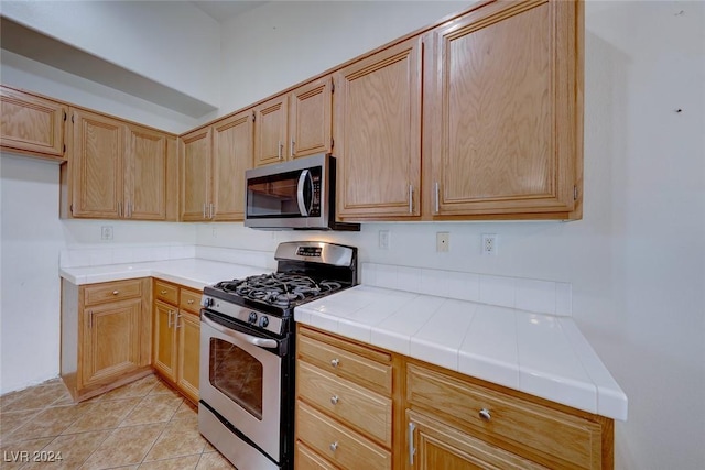 kitchen featuring tile counters, light tile patterned flooring, and stainless steel appliances