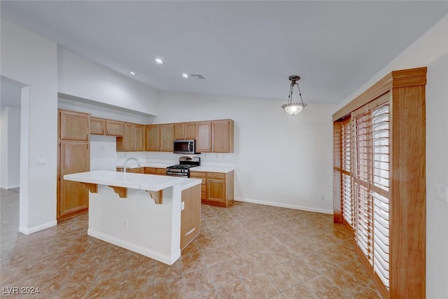 kitchen featuring a breakfast bar area, light tile patterned floors, an island with sink, decorative light fixtures, and stainless steel appliances