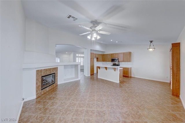 unfurnished living room featuring ceiling fan, a fireplace, light tile patterned floors, and vaulted ceiling