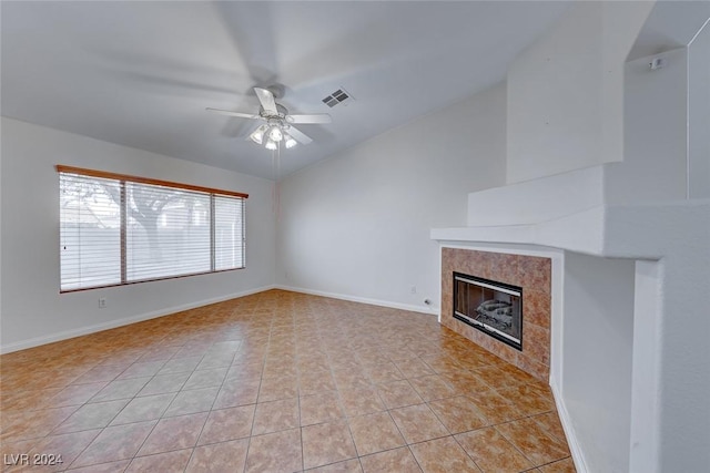 unfurnished living room with ceiling fan, lofted ceiling, a fireplace, and light tile patterned floors