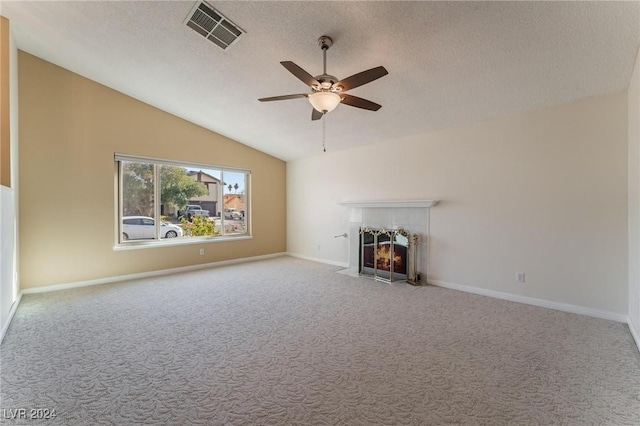 unfurnished living room featuring carpet, vaulted ceiling, ceiling fan, a textured ceiling, and a tiled fireplace