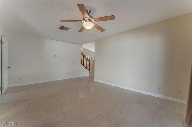 empty room with ceiling fan and a textured ceiling