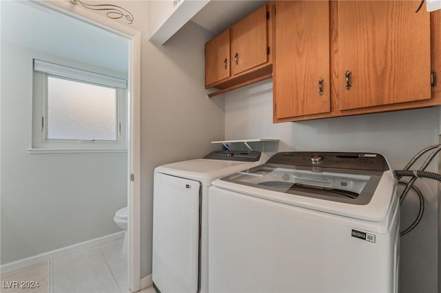 washroom with washer and dryer, light tile patterned flooring, and cabinets