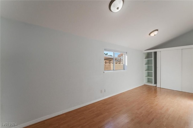 unfurnished bedroom featuring hardwood / wood-style flooring, a closet, and lofted ceiling