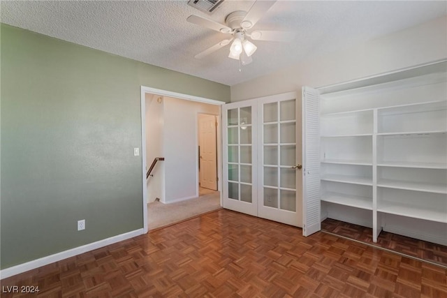 empty room with french doors, dark parquet flooring, a textured ceiling, and ceiling fan