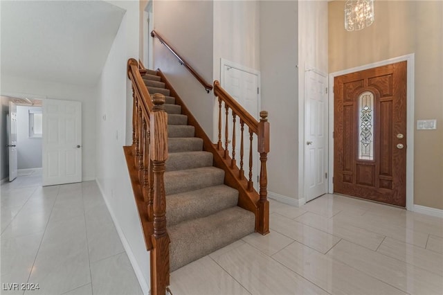 tiled foyer entrance with a chandelier