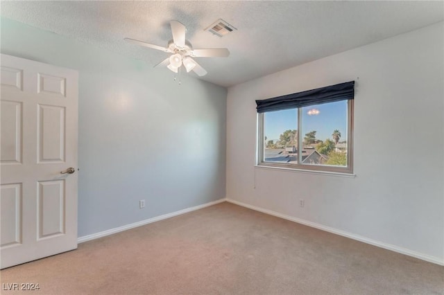 spare room with ceiling fan, light colored carpet, and a textured ceiling