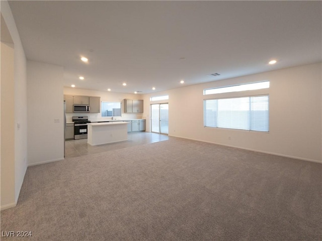 unfurnished living room featuring light colored carpet and sink