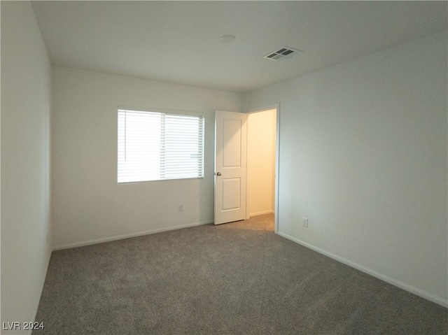 unfurnished room with dark carpet