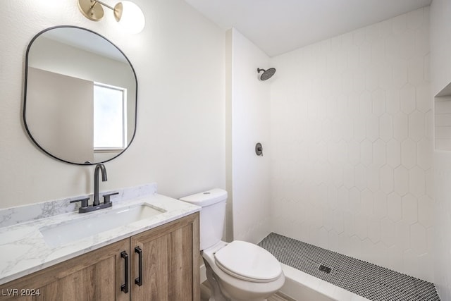 bathroom featuring tiled shower, vanity, and toilet