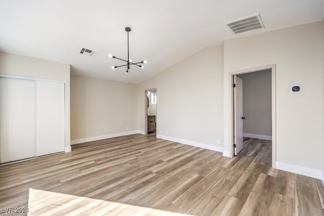 interior space featuring a chandelier, vaulted ceiling, light hardwood / wood-style flooring, and a closet