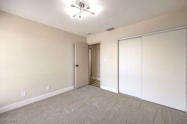 unfurnished bedroom with light carpet, a chandelier, and a closet