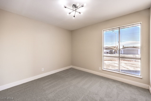 unfurnished room featuring carpet floors and an inviting chandelier