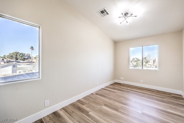 spare room featuring vaulted ceiling and light hardwood / wood-style flooring