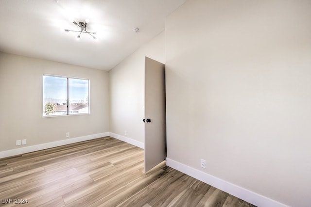 empty room featuring vaulted ceiling and light wood-type flooring