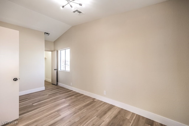 spare room with light hardwood / wood-style flooring and lofted ceiling