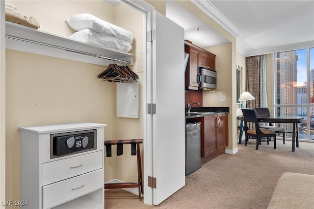 kitchen featuring light colored carpet, ornamental molding, and appliances with stainless steel finishes