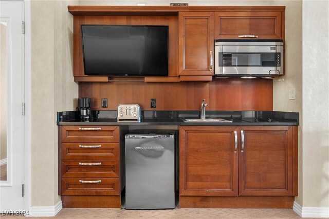 135 E Harmon Ave Unit 407, Las Vegas, NV 89109 - kitchen featuring brown cabinetry, a sink, stainless steel microwave, and dark countertops