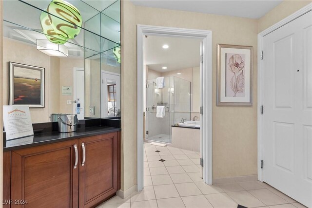 135 E Harmon Ave Unit 407, Las Vegas, NV 89109 - bathroom featuring tile patterned flooring, vanity, a bath, baseboards, and a stall shower