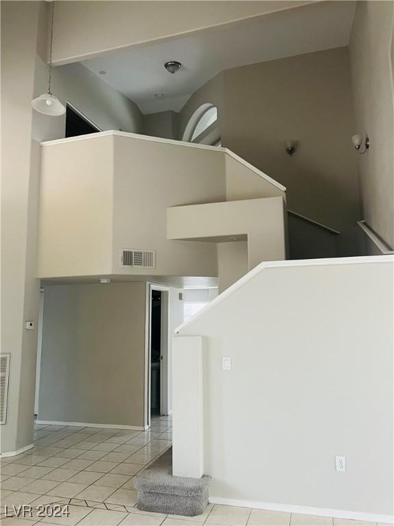 interior space featuring a towering ceiling and light tile patterned flooring