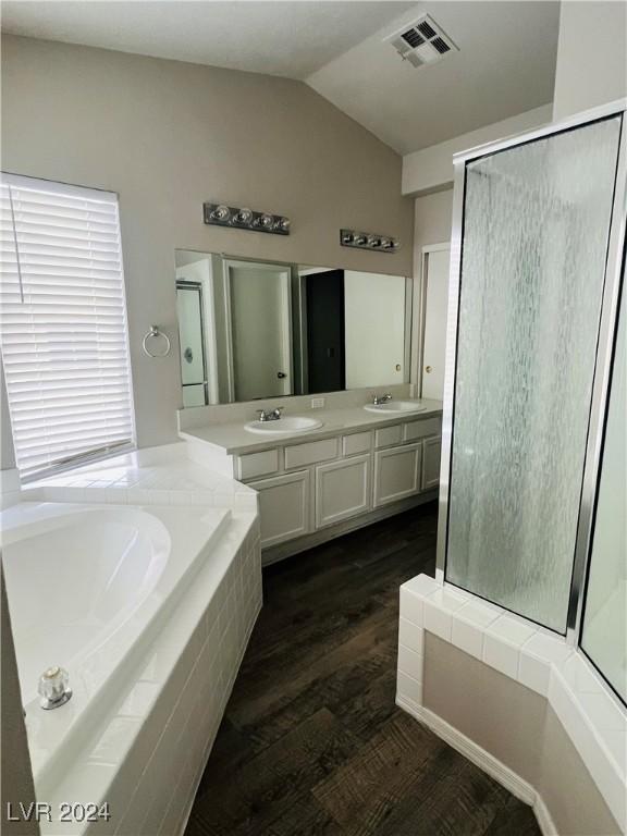 bathroom with vanity, lofted ceiling, wood-type flooring, and plus walk in shower