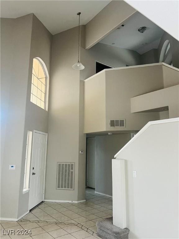 entryway with light tile patterned flooring and a towering ceiling