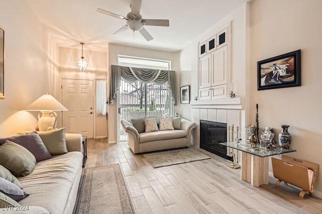 living room with ceiling fan and a tiled fireplace