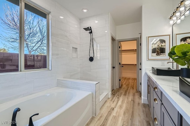 bathroom featuring vanity, hardwood / wood-style floors, and plus walk in shower