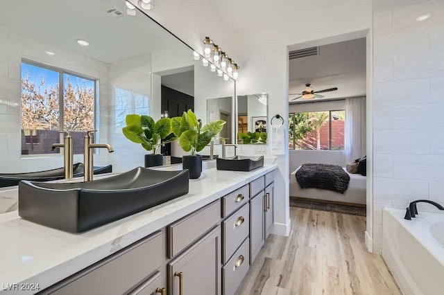 bathroom with ceiling fan, vanity, a bathtub, and wood-type flooring