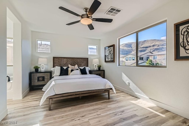 bedroom with ceiling fan, a mountain view, and light hardwood / wood-style flooring