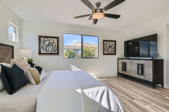 bedroom with ceiling fan, multiple windows, and light hardwood / wood-style flooring