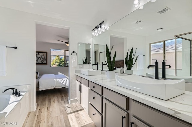 bathroom with hardwood / wood-style flooring, ceiling fan, vanity, and a tub to relax in