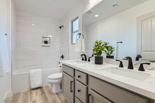 full bathroom featuring hardwood / wood-style flooring, vanity, toilet, and tiled shower / bath combo