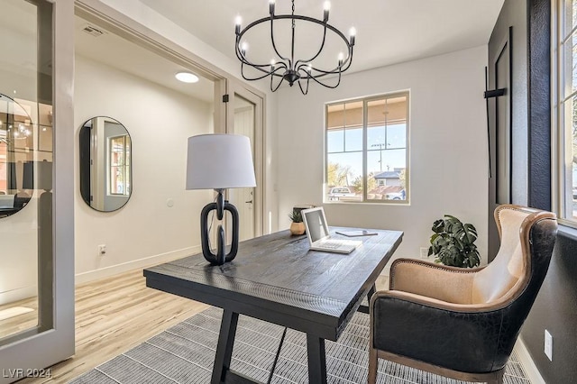 home office with a chandelier and light hardwood / wood-style flooring