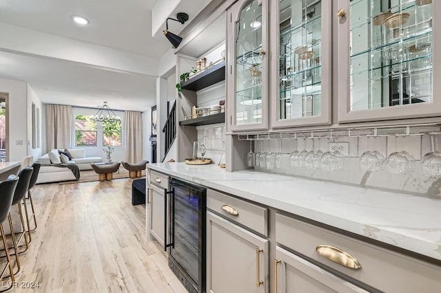 bar with light stone countertops, wine cooler, backsplash, and light hardwood / wood-style floors