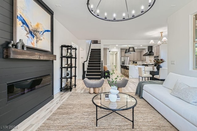 5873 Skyfall Ct, Las Vegas, NV 89135 - living room featuring a chandelier, light wood-style flooring, a glass covered fireplace, and stairs