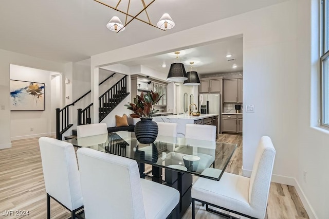 dining space featuring an inviting chandelier, sink, and light wood-type flooring